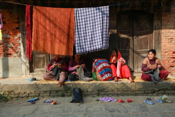 A group of women engaged in textile weaving on a vibrant street, showcasing traditional skills.