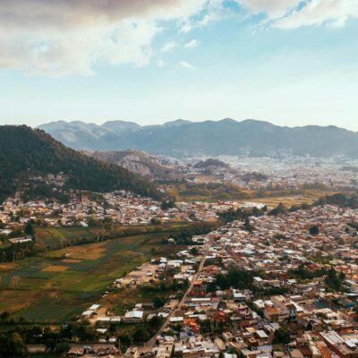 Scenic aerial view of a city with mountains in the background under a partly cloudy sky.