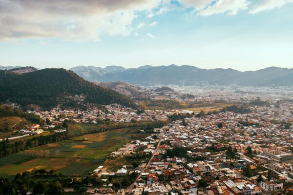 Scenic aerial view of a city with mountains in the background under a partly cloudy sky.