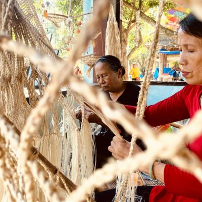 Women weaving traditional hammocks with skilled craftsmanship in a cultural setting.