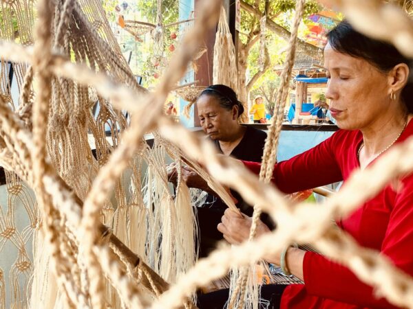 Women weaving traditional hammocks with skilled craftsmanship in a cultural setting.